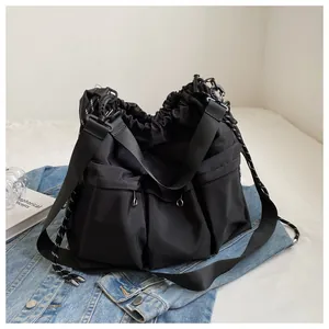 Detail of black waterproof nylon tote bag with drawstring closure and three front pockets