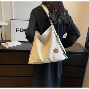 Detail of cream casual tote bag with adjustable strap and brown leather logo patch