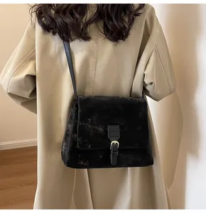Detail of vintage black suede messenger bag with gold buckle on a stylish female model