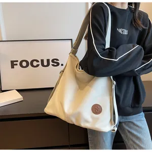 Lifestyle shot of large beige canvas tote bag with leather logo detail on shoulder