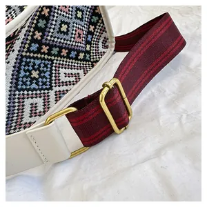 Close-up of geometric ethnic embroidery with striped strap and bronze buckle detail