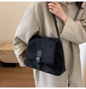 Detail of vintage black suede messenger bag with silver buckle and thin leather shoulder strap