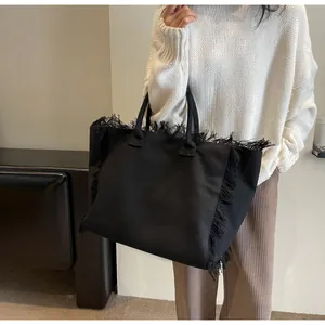 Gros plan sur un sac cabas en toile noire avec franges élégantes pour un look décontracté
