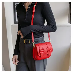 Detail of red leather crossbody bag with double gold square buckles and adjustable strap