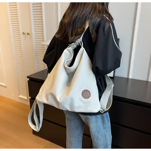 Large cream canvas tote bag with adjustable shoulder straps and brown leather badge detail