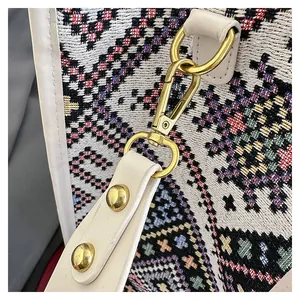 Detailed close-up of ethnic woven fabric and white leather strap with gold metal hooks