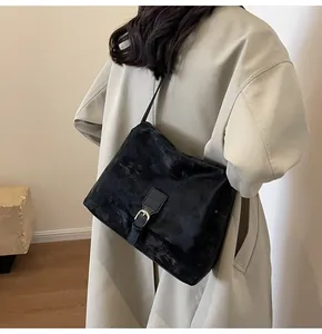 Close-up of black retro messenger bag with vintage texture worn over a beige trench coat