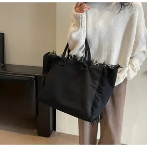 Détail du sac cabas en toile noire avec bordures à franges élégantes et grande capacité