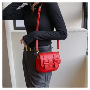 Detail view of the red PU leather crossbody bag featuring gold hardware and flap buckles