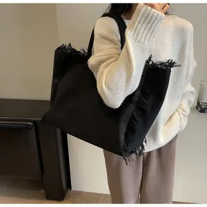 Gros plan d'un sac cabas en toile noire montrant des franges et une texture tissée