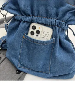 Detail view of denim bucket bag showing outer pocket storage capacity for a phone