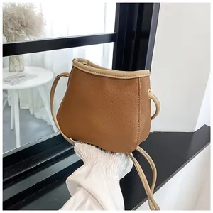 Sac seau marron avec texture litchi, bordure blanc cassé et fine bandoulière