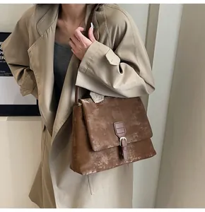Detail of distressed brown retro messenger bag with vintage strap and buckle decoration