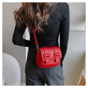 Detail view of red leather crossbody bag with gold metal buckles and sleek retro design