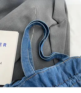 Close-up of reinforced shoulder strap and orange stitching on denim bucket bag
