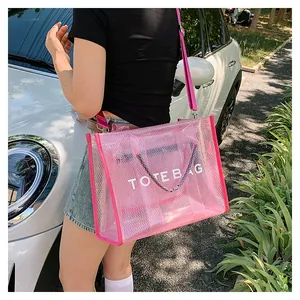Pink transparent mesh tote bag with white TOTE BAG text shown on model in outdoor setting