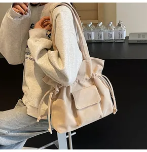 Detail of corduroy bucket bag with drawstring closure and front flap pocket shown on model