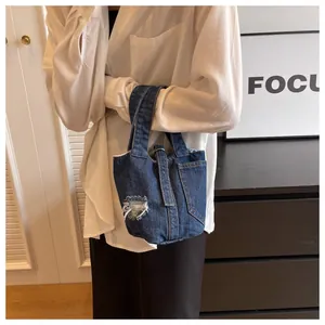 Λεπτομέρεια της denim τσάντας κουβά με σκισμένη υφή και κομψή μεταλλική αγκράφα