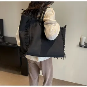 Gros plan d'un sac cabas en toile noire avec des bords à franges et des anses épaisses