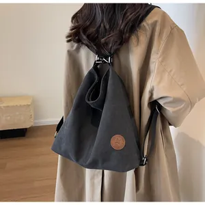 Detail of minimalist black canvas tote bag with brown leather logo and silver metal hooks