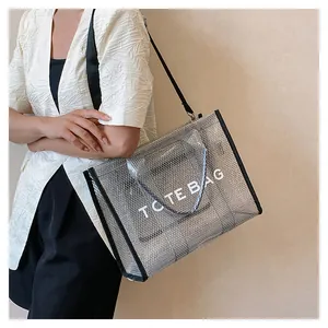 Detail of silver mesh tote bag with black strap and TOTE BAG print worn by model