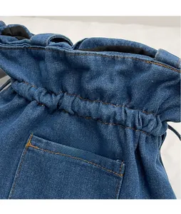 Detail of blue denim bucket bag with orange contrast stitching and textured fabric