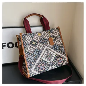 Detailed close-up of ethnic woven tapestry tote bag with leather trim and metal hardware