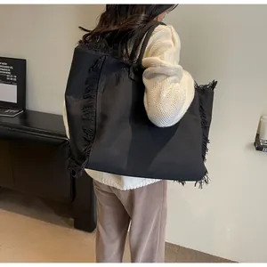 Détail du grand sac cabas en toile noire avec bords à franges et doubles anses
