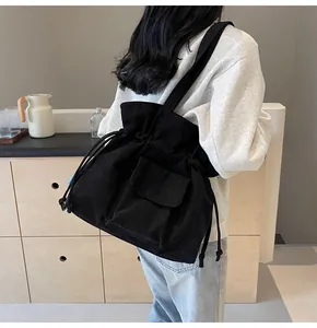 Detail der schwarzen Cord-Beuteltasche mit Kordelzug und Fronttasche am Modell getragen