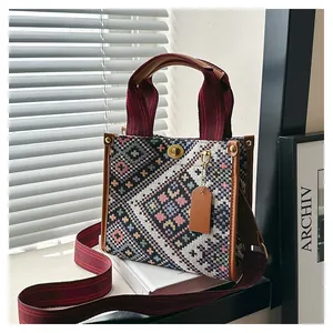 Detail of woven jacquard tote bag with burgundy straps and golden twist-lock closure