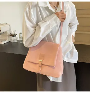 Detail view of pink suede messenger bag with metal buckle on a shoulder strap