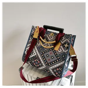Ethnic woven tote bag with geometric patterns displayed on a white suitcase