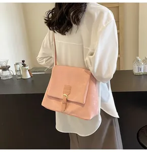 Detail view of pink flap crossbody bag showing matte texture and metal buckle on the model