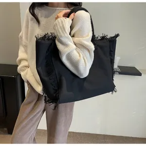 Détail macro du sac cabas en toile noire avec bords à franges et texture tissée