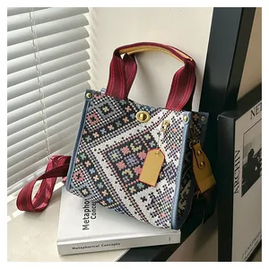 Detail of ethnic geometric woven tote bag with gold twist lock and red striped handles
