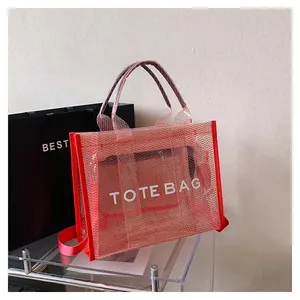 Close-up of a red mesh tote bag with white text and a dark semi-transparent inner pouch