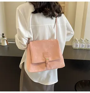 Detailed view of pink faux suede messenger bag with vintage metal buckle on shoulder strap