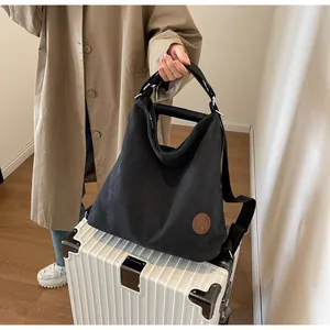 Detail of large black canvas tote bag with brown logo patch on a suitcase