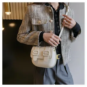 Detail view of cream white saddle bag showing fine leather texture and golden hardware