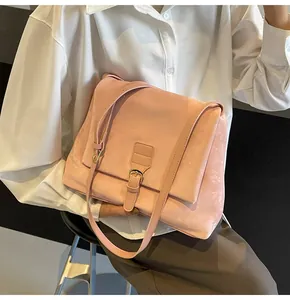Detail of a vintage pink suede messenger bag on model with adjustable strap and buckle