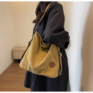 Close-up of mustard yellow canvas tote bag with adjustable strap and embossed leather logo
