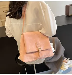 Close-up of pink messenger bag with a soft leather texture and golden metal buckle