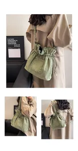 Detail of grey denim bucket bag with drawstring closure and wide shoulder strap design