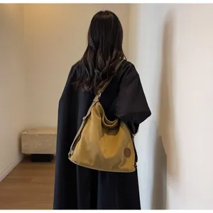 Rear view of model wearing a large mustard yellow canvas tote bag with a dark coat