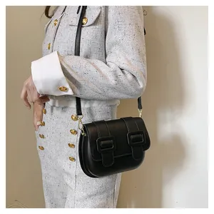 Detailed side view of a black leather crossbody bag with double square buckle accents