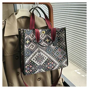 Detail of ethnic jacquard tote bag featuring colorful geometric patterns and red handles