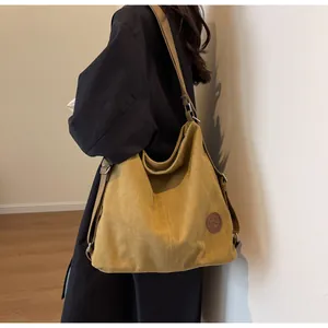 Close-up of bright yellow canvas tote bag featuring texture and leather brand patch
