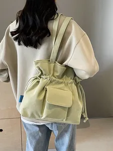 Borsa a secchiello in velluto a coste verde salvia con coulisse e tasca frontale indossata
