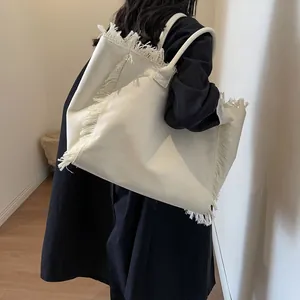 Grand sac cabas en toile blanc cassé avec franges porté par un mannequin pour le quotidien