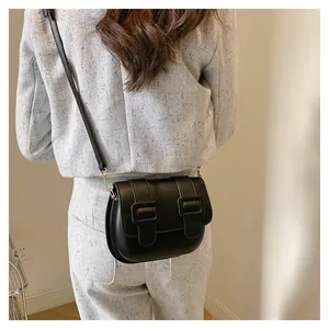 Detail of a black leather saddle crossbody bag showing its compact size and back view